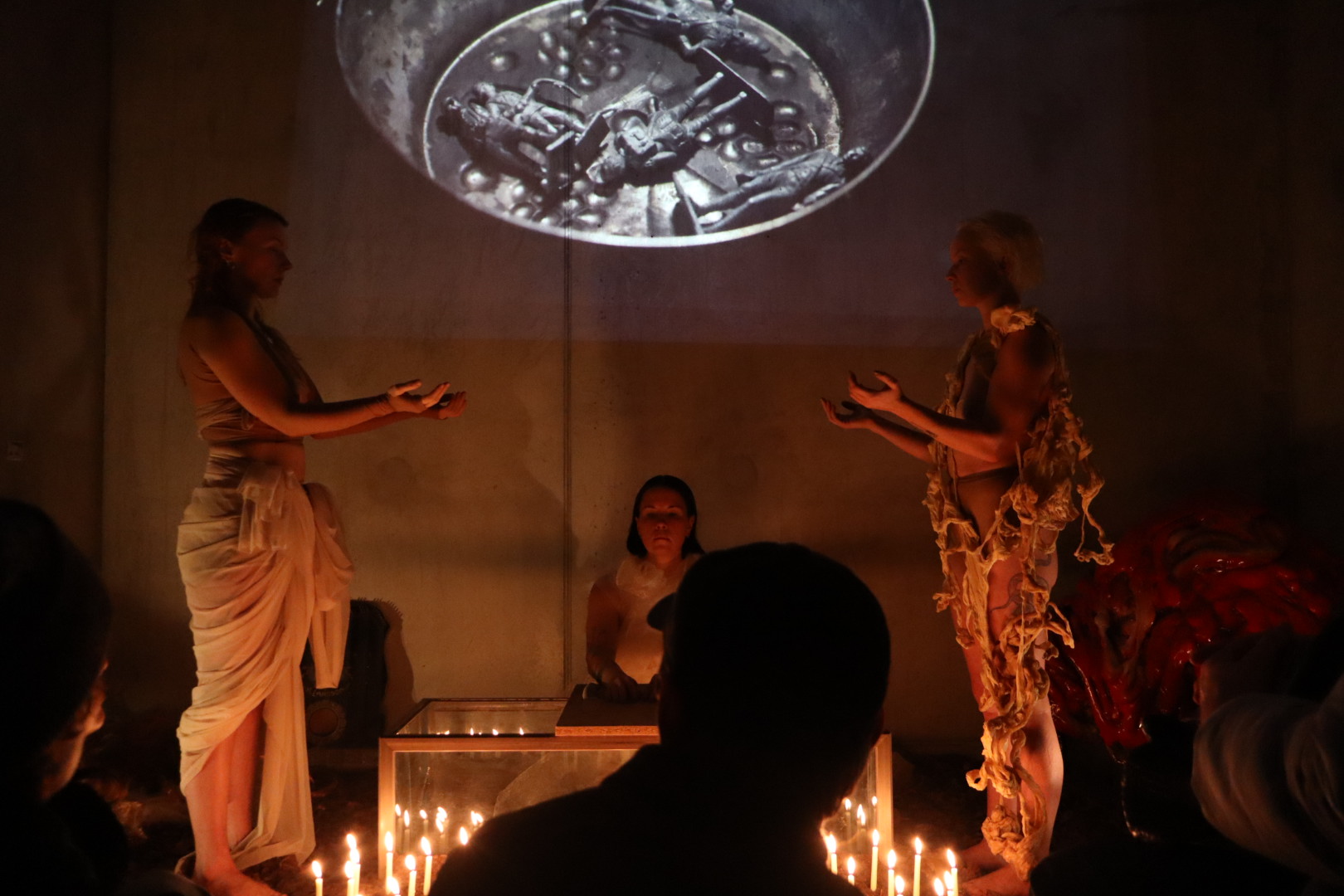 Three performers facing the audience beneath a projected image in Midnight Mass