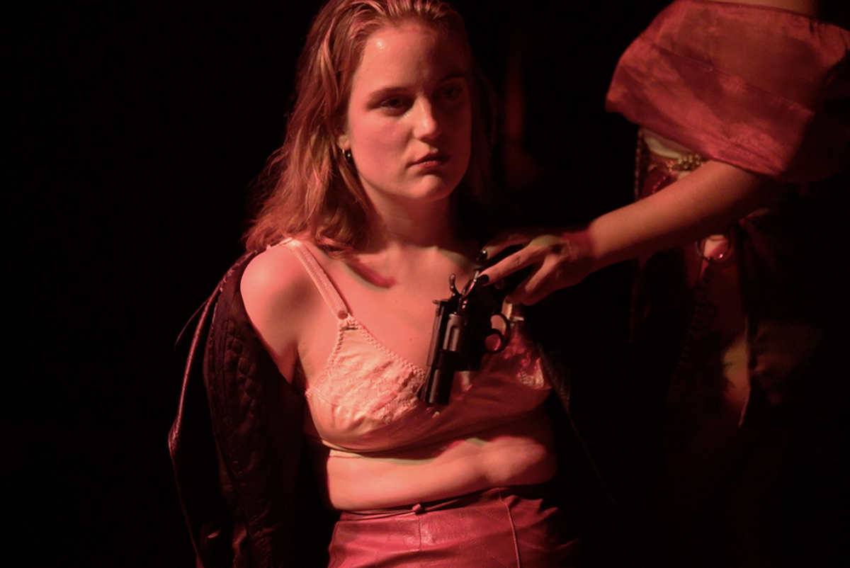 Seated performer with a prop gun in The Roost Social Club
