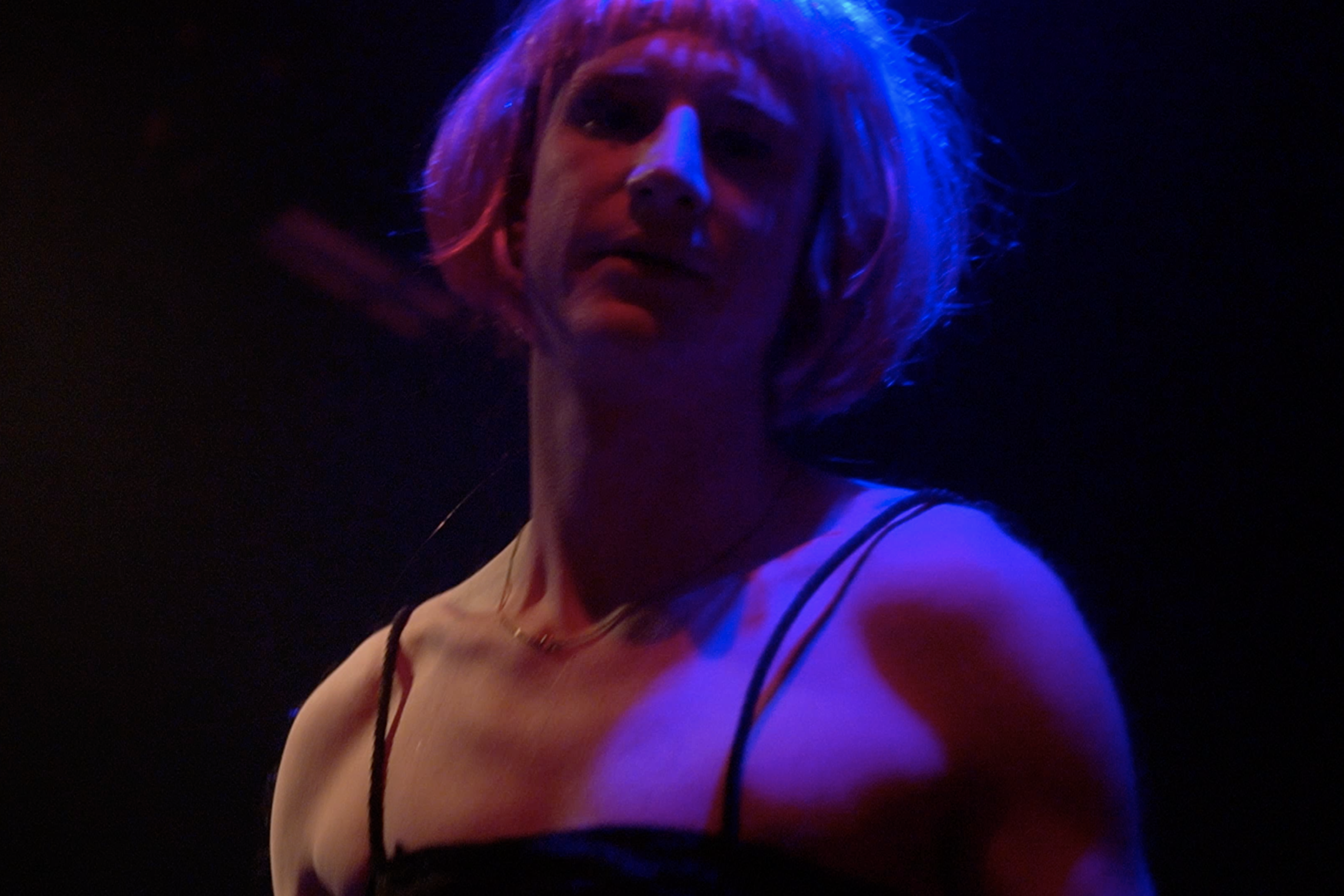 Close view of a performer under blue and red stage light in The Roost Social Club